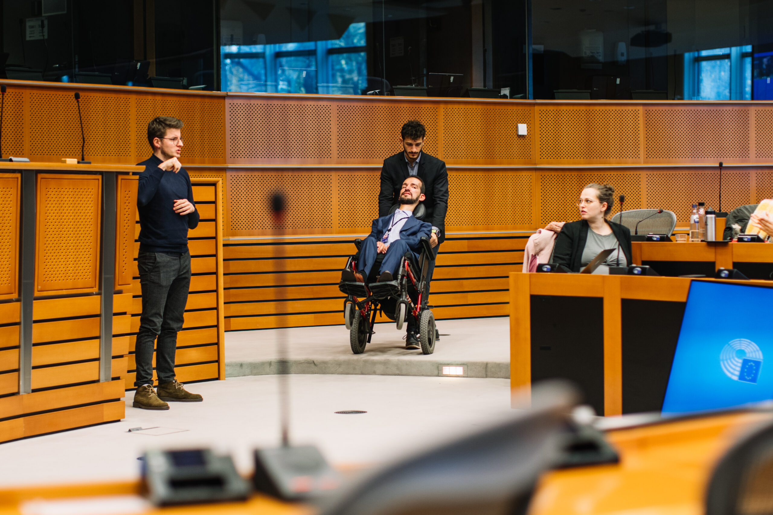 MEP and his personal assistant moving in the Parliament room, obstacle prevent them from moving normally.