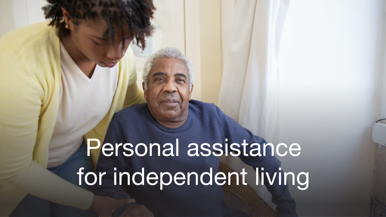 Person sat in his wheelchair with his personal assistant taking care of him