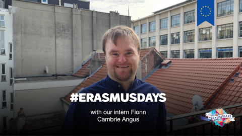 Fionn is smiling, standing on a balcony, in Brussels. Text says "Erasmus Days with our new intern Fionn Cambrie Angus". EU logo appearing on the image.