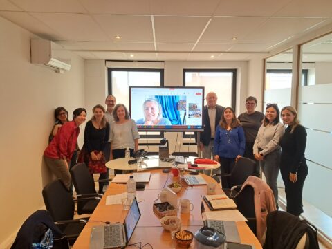 A group of people standing at the end of the desk smiling at the camera