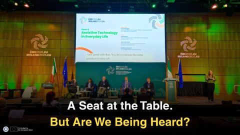 Article graphic titled “A Seat at the Table. But Are We Being Heard?” Five panellists, including wheelchair users, sit onstage beneath a screen reading “Assistive Technology in Everyday Life.” A sign language interpreter stands to the right, with audience members in the foreground. ENIL and EU co-funding logos appear at the bottom left.