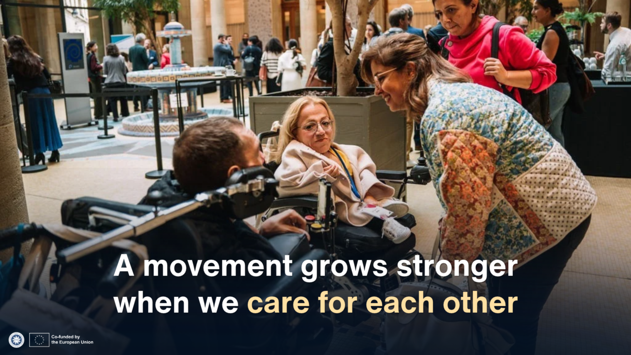 Freedom Drive participants, including two wheelchair users, chat together at an indoor reception. Overlaid text reads: “A movement grows stronger when we care for each other.”