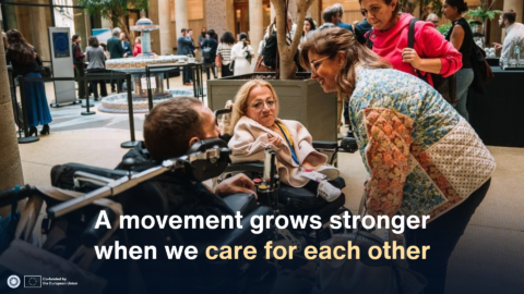 Freedom Drive participants, including two wheelchair users, chat together at an indoor reception. Overlaid text reads: “A movement grows stronger when we care for each other.”