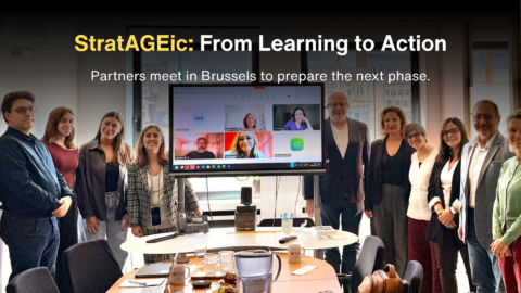 Group photo of StratAGEic project partners meeting in Brussels, with several people standing around a conference room and additional participants joining on a large screen. Overlaid text reads: “StratAGEic: From Learning to Action” and “Partners meet in Brussels to prepare the next phase.”